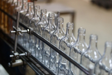 Empty glass bottles on the conveyor. Factory for bottling alcoholic beverages.