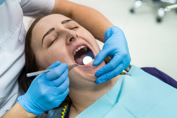 Doctor in dentistry examining patient's teeth with mirror