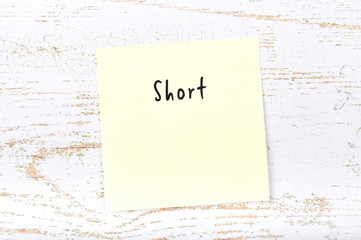 Yellow sticky note with handwritten word short