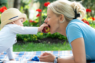 Happy loving mother and her baby eat an apple