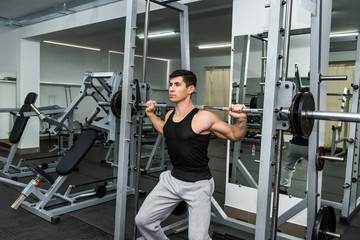 Athletic  man lifting dumbbell in gym on shoulders