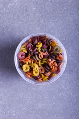 Multicolored pasta with the addition of natural vegetable dye. In a jar on a concrete table. Top view, copy Space.