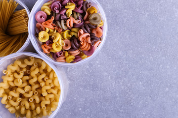 Multicolored pasta with the addition of natural vegetable dye. In a jar on a concrete table. Top view, copy Space.