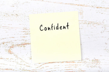 Yellow sticky note with handwritten word confident
