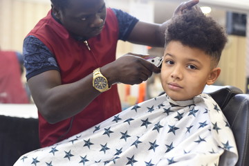 Boy in the african barbershop. Cute mixed boy makes a haircut in the African salon. Hair style....