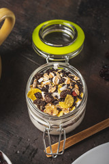 Glass full of white yogurt and muesli on dark wooden board