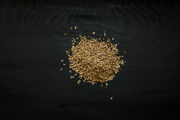 Close-up image of anise seeds on black wood background, view above
