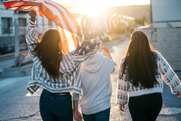 Group of happy friends with the American flag on the street