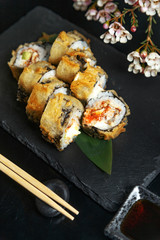 Fresh sushi rolls on black slate. Restaurant table setting.