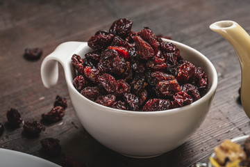White cup full of dried red berries placed on dark board