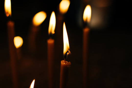 candles in black darkness environment in religious service time inside church, yellow glared bokeh effect