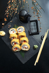 Fresh sushi rolls on black slate. Restaurant table setting.
