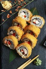 Fresh sushi rolls on black slate. Restaurant table setting.