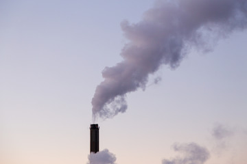 Smoke coming from a heat plant chimney on a cold winter evening