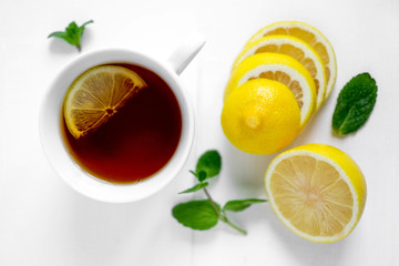 Photo of a cup of tea with lemon and mint. White cup of tea with lemon. Drink for convalescence. Vitamin C.