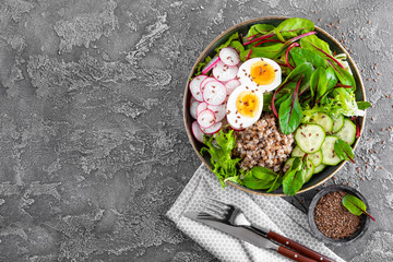 Buddha bowl dish with buckwheat porridge, boiled egg, fresh vegetable salad of radish, cucumber, lettuce and chard leaves. Healthy lunch menu. Top view