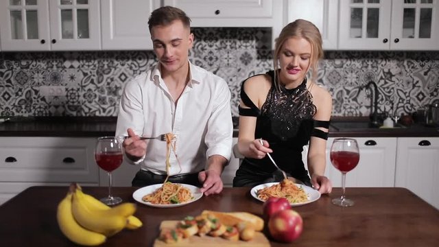 Romantic young couple eating pasta in kitchen