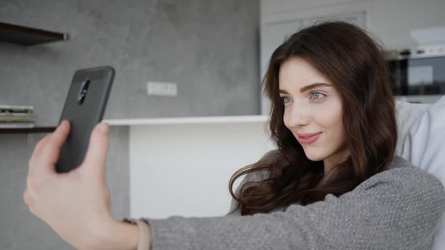 Beautiful young woman at home spin in rotating chair taking phone selfie pictures