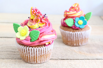 Colorful cupcakes with sugar flowers on a wooden table.  Close-up