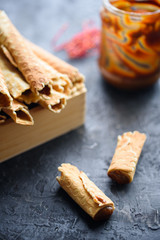 Wafer rolls, tasty and fragrant, with boiled condensed milk on a black table