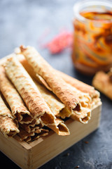 Wafer rolls, tasty and fragrant, with boiled condensed milk on a black table