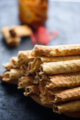 Wafer rolls, tasty and fragrant, with boiled condensed milk on a black table