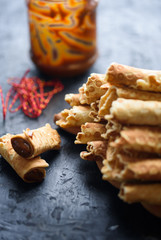 Wafer rolls, tasty and fragrant, with boiled condensed milk on a black table