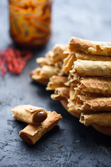 Wafer rolls, tasty and fragrant, with boiled condensed milk on a black table