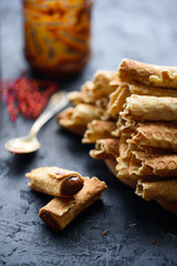 Wafer rolls, tasty and fragrant, with boiled condensed milk on a black table