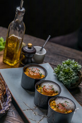 Orange pumpkin risotto with scallop and foamy sauce in black bowl on rustic wooden table