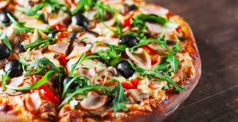 Pizza with Mozzarella cheese, mushrooms, ham, tomato sauce, pepper, olives, Spices and Fresh arugula. Italian pizza on wooden table background