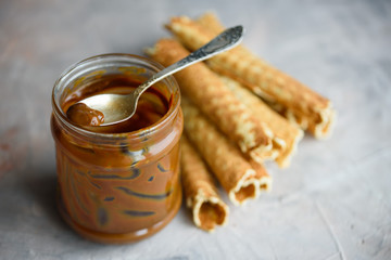 Waffle rolls, tasty and fragrant, with boiled condensed milk on a concrete background