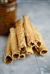 Waffle rolls, tasty and fragrant, with boiled condensed milk on a concrete background