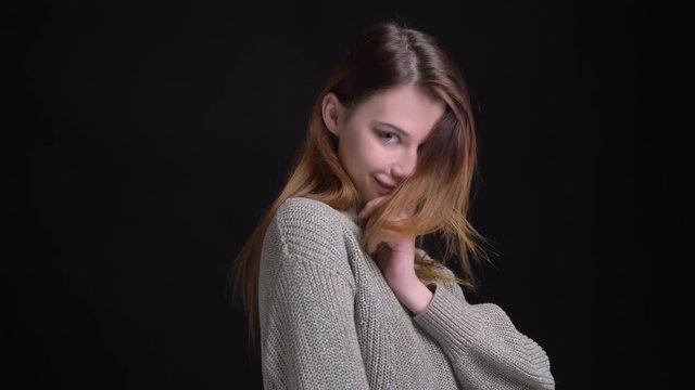Closeup portrait of young beautiful caucasian female model getting shy and playing with her hair looking seductively at camera