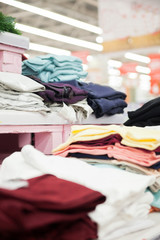 Many different clothes   on   shelves in   store.