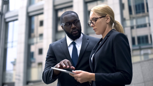 Colleagues consider project on tablet, marketers choose place for advertising