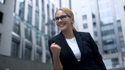 Business woman showing yes gesture, rejoices at promotion and successful career