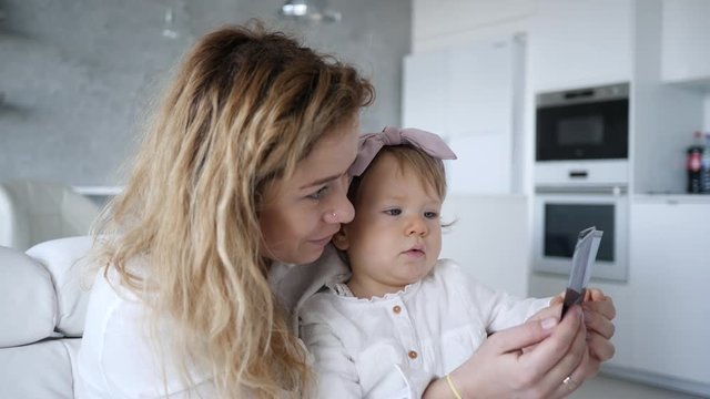 Mother with baby child daughter watching family photo album at home