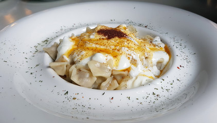 homemade delicious turkish manti ( turkish ravioli ) with yogurt and sauce.
