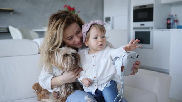 Mother with baby child daughter and pet dog take selfie picture for family photo album at home