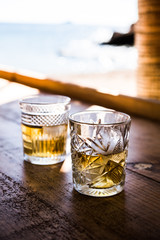 two glasses of hierbas on a wooden shelf at the beach