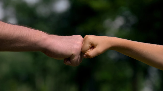 Man and child punching fists, parents as reliable support for children, closeup