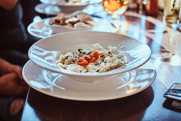 Close-up image of a salad on a white plate. Friends eat in the cafe outdoors