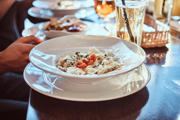 Close-up image of a salad on a white plate. Friends eat in the cafe outdoors