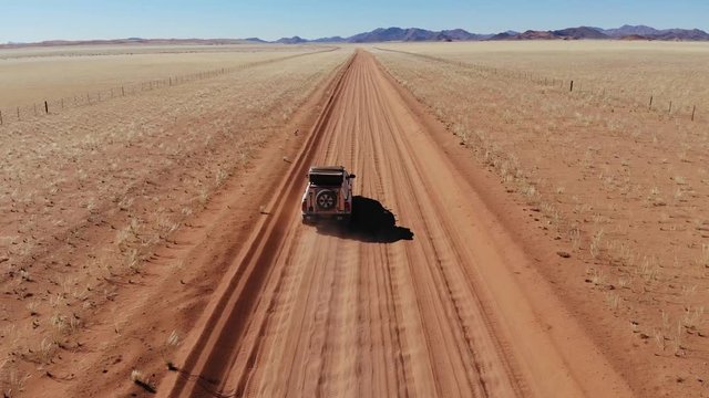 Aerial drone shot of Lonely 4x4 car driving through vast Namib Naukluft National Park, Namibia