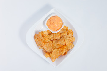 Corn chips in a white ceramic dish with cheesy dip