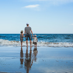 father and two daughters standing at the beach