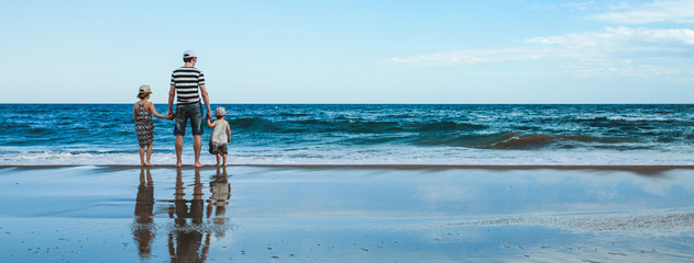 father and two daughters standing at the beach
