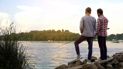 Fototapeta premium Father and teenager son fishing together, relaxing near lake, favorite hobby