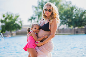 Fototapeta na wymiar pregnant with her daughter in the pool